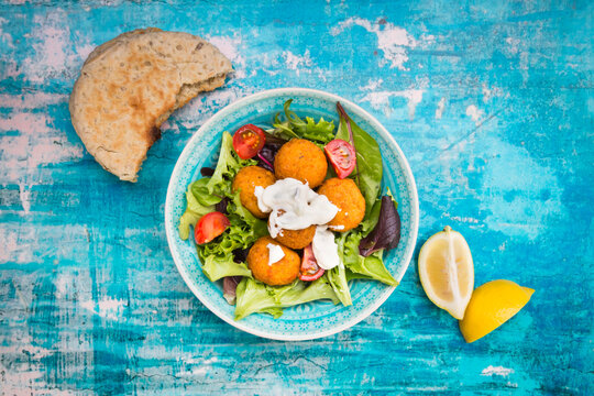 Bowl of mixed salad, tomato, sweet patato Falafel and yoghurt sauce with flat bread