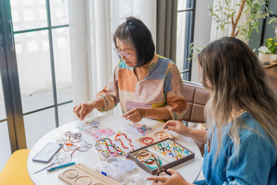 Two Asian woman making handcrafted jewelry together at home