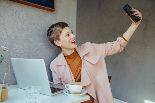 Woman taking a selfie with her laptop in a cafe