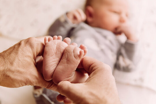 Feet of newborn baby boy being held by father?s hands