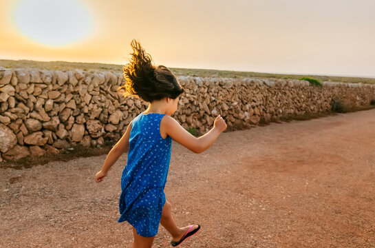 Little girl hopping on street at sunset