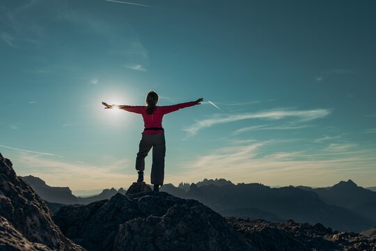 Woman hiking in the Dolomites mountains in Italy standing on summit