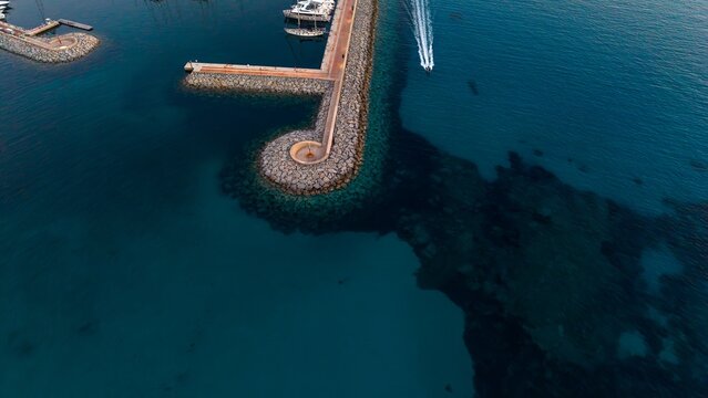Aerial view of a marina pier and boat in the blue sea