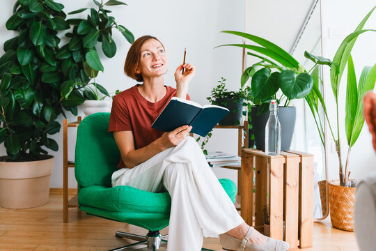 Thoughtful woman holds a notebook and plans in her home office