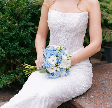 Bride holding wedding bouquet sitting on bench