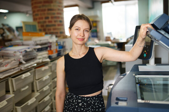 Young woman operates a large printer in the office