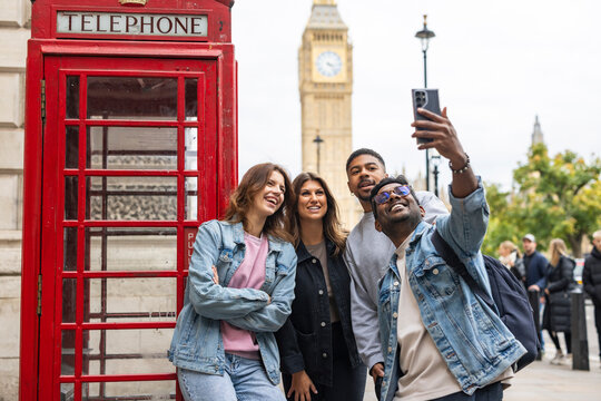 Group of friends taking a selfie in front of red telephone booth and Big Ben