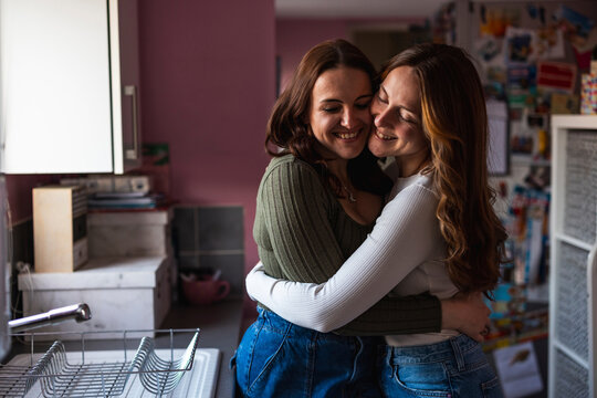 Lesbian couple sharing a candid affectionate hug in the kitchen