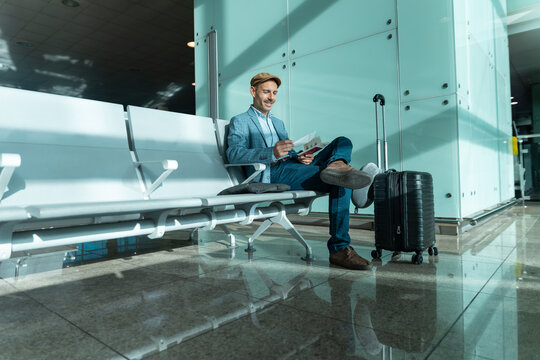 Male passenger sitting at Barcelona airport waiting with luggage