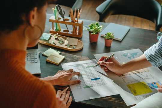 Colleagues analyzing business graphs and documents at office desk