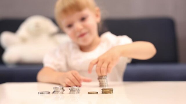 A preschooler counts coins on a living room table. Financial scarcity training. Kids and money. Savings, personal finance