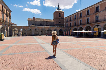 Female tourist with hat walking across historic main square plaza in Spain © M.studio