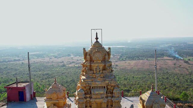A drone video of historical old hindu temple located on top of hill amidst lush green farmlands