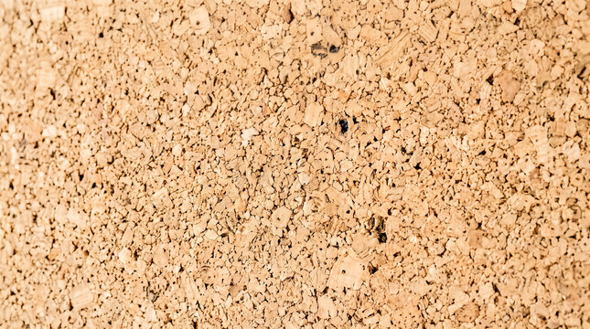 Close macro view displaying natural light brown cork board material surface featuring detailed uneven organic texture patterns presenting blank empty indoor background