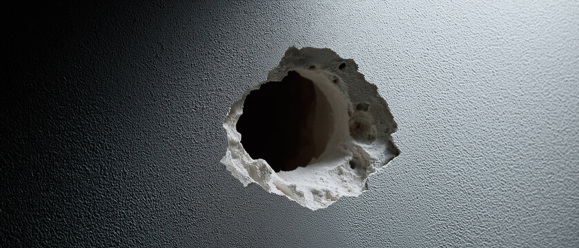 Large round broken hole damaged through dark textured plaster drywall inside an interior room space.
