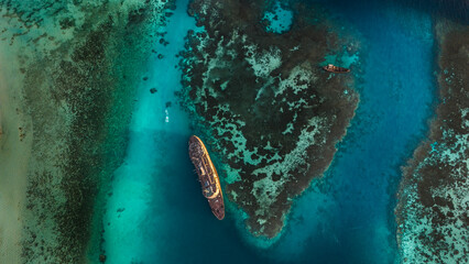 Top-down aerial drone view of a rusty shipwreck stranded on the coral reefs of the Red Sea near Jeddah, Saudi Arabia. © hasan