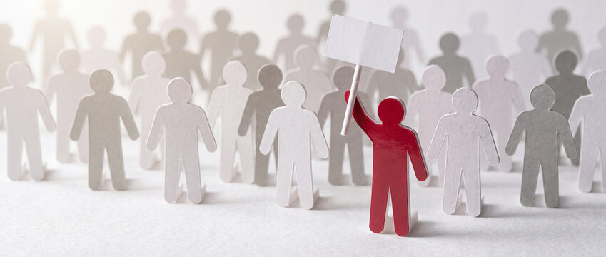 Papercraft concept of a red figure holding a blank white sign in front of a crowd of grey figures, symbolizing leadership, protest, and individuality