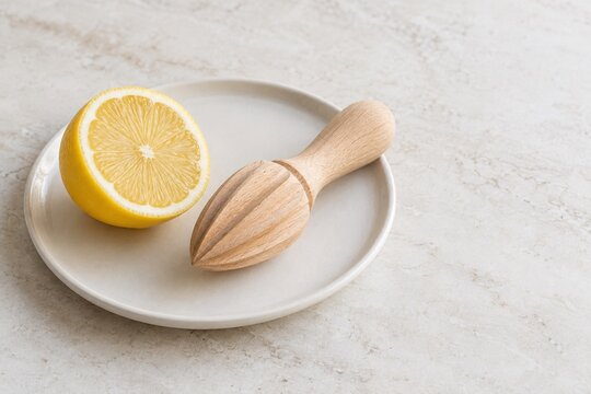 Wooden citrus reamer and fresh lemon half on a ceramic plate