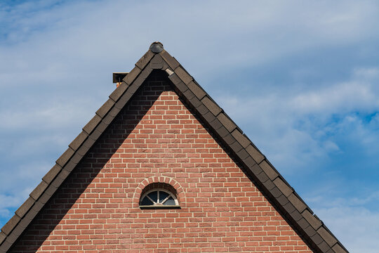 Roof structure of a brick house against a blue sky
