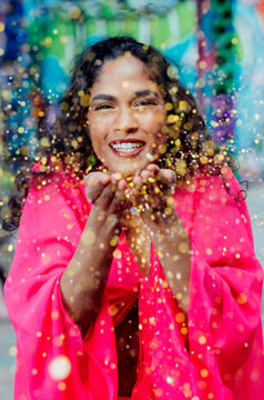 South Asian woman blowing glitter