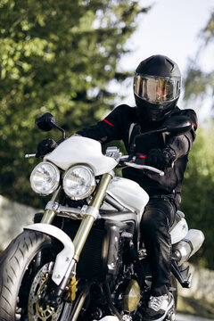Person riding a powerful white motorcycle, wearing a black helmet and protective gear, enjoying a journey on the road