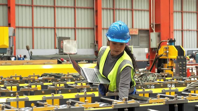 Female Engineer Inspect Automated Factory Machinery With Laptop : Professional Asian female technician hardhat check industrial roll forming line use laptop computer in manufacturing plant.