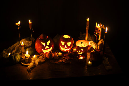 Happy Halloween. Carved glowing halloween pumpkins, burning candles and spooky spiders in dark. Atmospheric halloween night with jack o lantern decorations. Boo. holiday banner