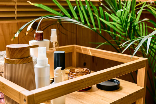 Skincare and beauty products, facial cream, towels and a houseplant arranged on a wooden tray in warm natural sunlight, representing personal care and a daily beauty routine.
