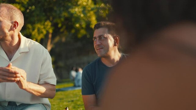 Group gathers in park for summer afternoon, sharing stories and enjoying relaxed atmosphere