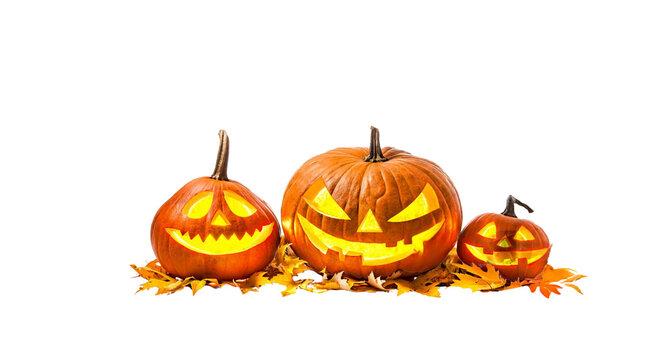 Three glowing jack-o'-lantern pumpkins sitting on dry autumn leaves isolated on black background