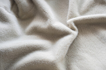 Soft gray wool blanket close-up texture with cozy fur pile for interior. Gentle folds for home. © Iryna