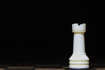 White rook chess piece, dark background. © Ana Maria