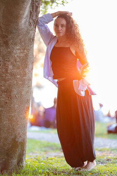 Woman standing by tree at sunset feeling calm