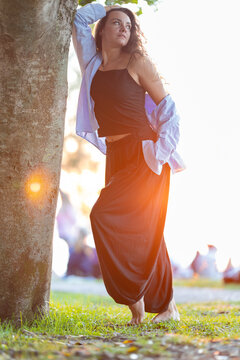 Woman posing against tree in golden hour sunlight