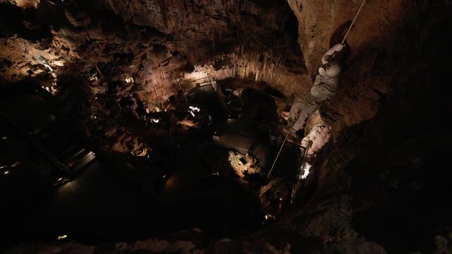 Explorer rappelling down into a deep cave