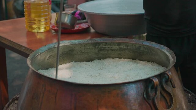 Chef Stirring Uzbek Plov in Huge Traditional Metal Kazan, Close Up