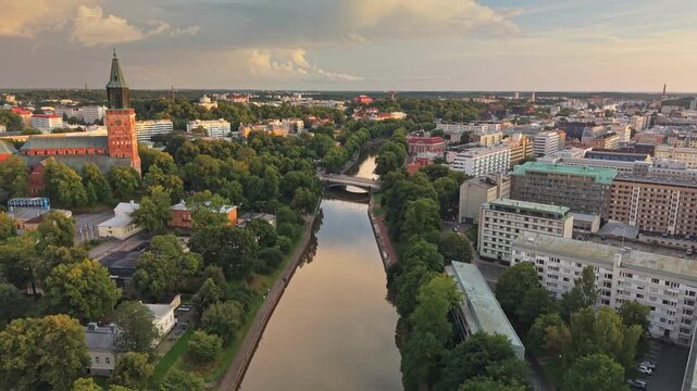 Aerial flight over aura river flowing through Turku city in southwest Finland. Historic cathedral stands tall in summer evening. Turku city and its prominent medieval cathedral in Finland