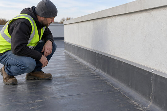 Technician inspecting parapet base roof membrane termination