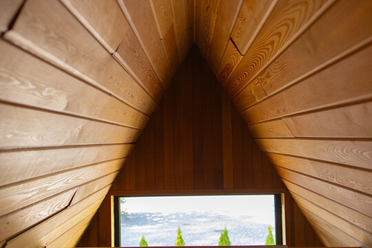 Wooden A-frame gable interior with plank ceiling and window view
