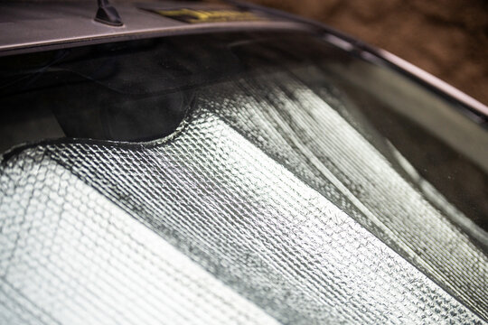 Closeup of protective reflective surface under windshield of passenger car parked on hot day, heated by sun rays inside car. Sunshade, heat protection, vehicle accessory concept