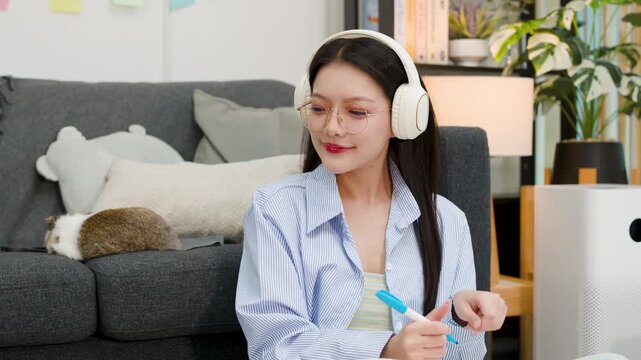 Asian Woman Working Remotely Petting Rabbit in Living Room