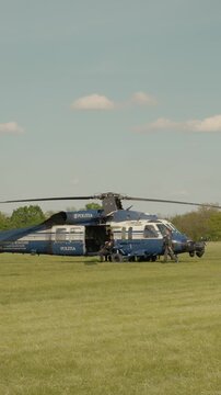 Vertical Screen A police helicopter gets ready to take off at an air show held at a local airport. Ground crew prepares the aircraft and ensures safety before departure.