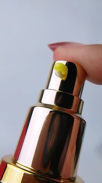 Golden spray bottle packaging dispensing thick creamy yellow liquid when the top cap is pressed. Rich cosmetic texture, luxury skincare product concept with a smooth, dense formula.