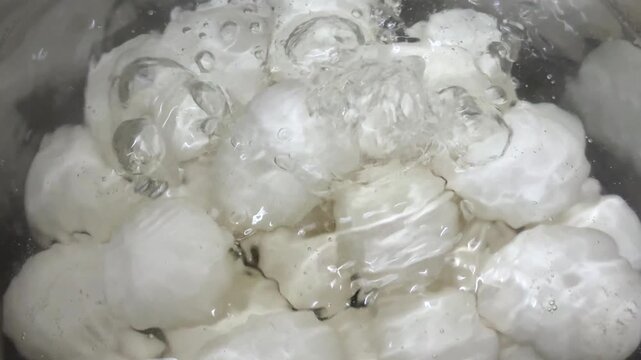 White eggs are boiling in a pot of water, close up