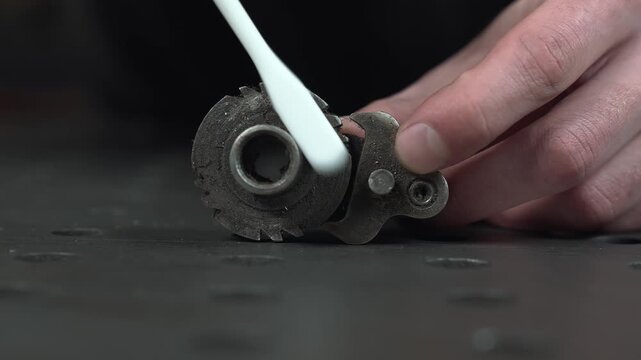 The worker cleans the bearing mechanism, removing caked-on dirt, dust, and oil. He scrubs it with a cloth and a brush.