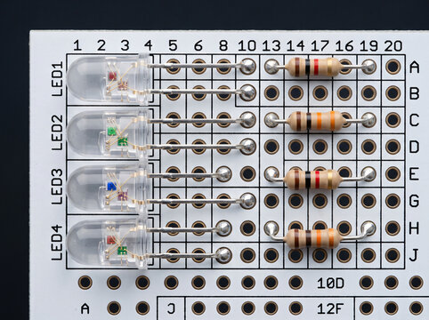 Through hole leds with resistors installed on white breadboard prototype.