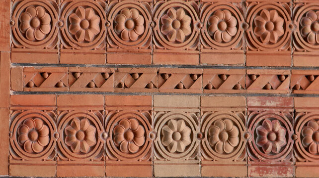 Ancient terracotta tiles texture. Historical ceramic building facade with relief floral rosette pattern background full frame.