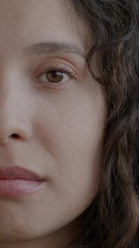 Close-up portrait of nervous Middle Eastern woman looking at camera pursing lips feeling insecure on black studio background. People and emotion concept.