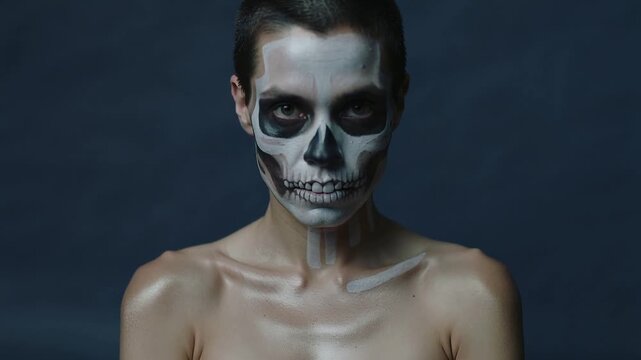 Starting skull-painted model lifting chin, rotating head slightly in studio, showing clavicle paint
