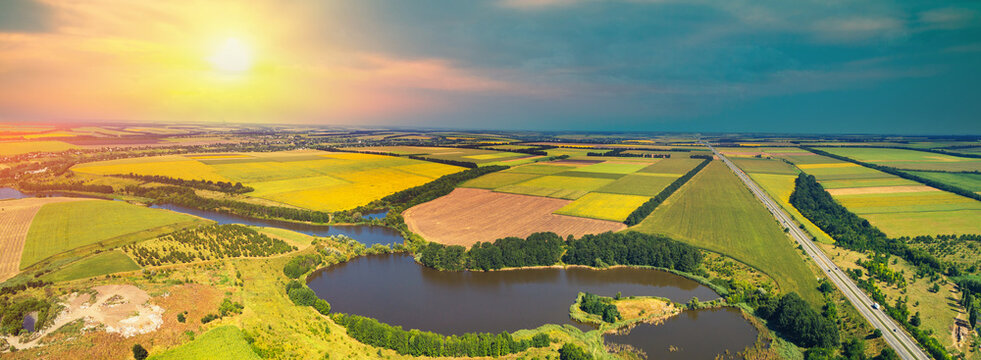 Rural landscape with beautiful sky, aerial view. View of colorful arable fields, lake and highway in summer